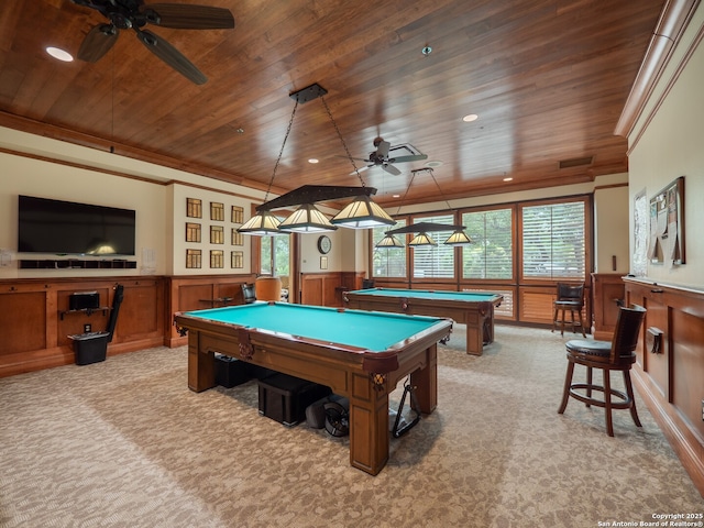 rec room with a wainscoted wall, crown molding, light colored carpet, wood ceiling, and a healthy amount of sunlight