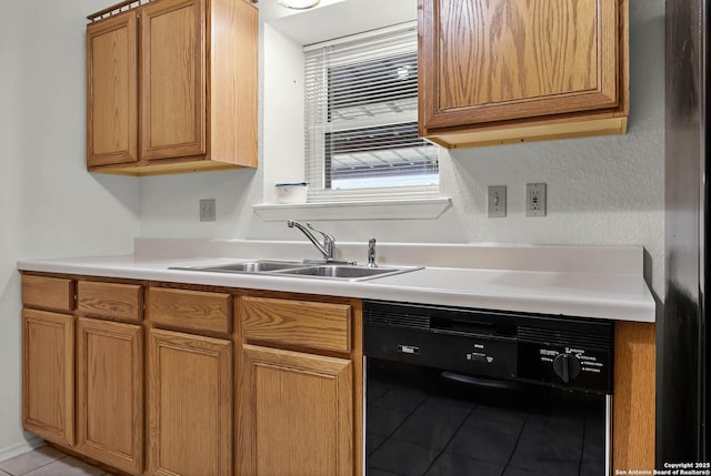 kitchen with light tile patterned floors, a sink, light countertops, black appliances, and brown cabinetry