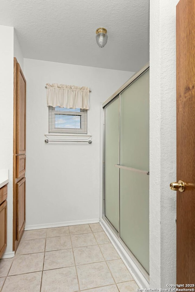 bathroom with a stall shower, tile patterned flooring, vanity, and a textured ceiling