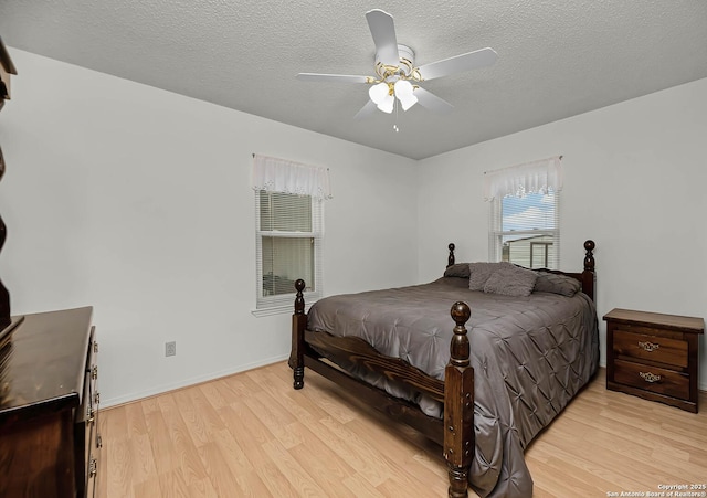 bedroom with a textured ceiling, baseboards, a ceiling fan, and light wood-style floors