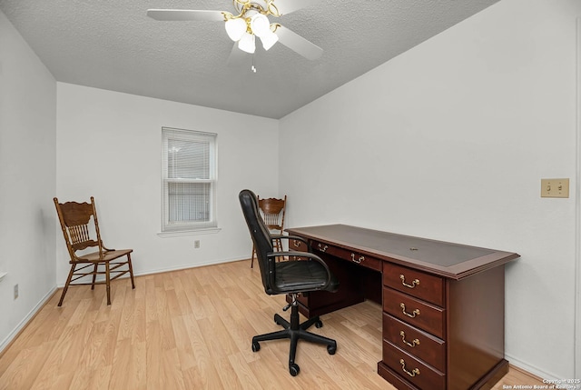 office area featuring a textured ceiling, light wood-type flooring, a ceiling fan, and baseboards