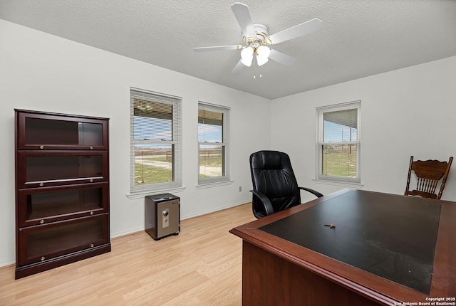 office area with a healthy amount of sunlight, light wood-type flooring, and a textured ceiling