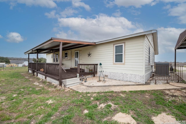 view of front facade featuring central AC unit, a front yard, and a wooden deck