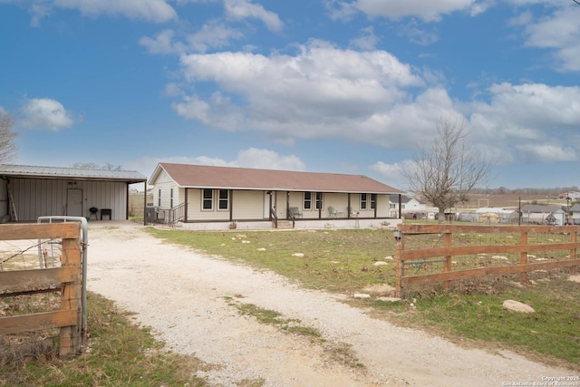 view of front of house with a porch, fence, and dirt driveway