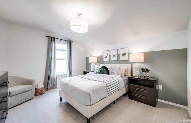 bedroom with baseboards, vaulted ceiling, and light colored carpet