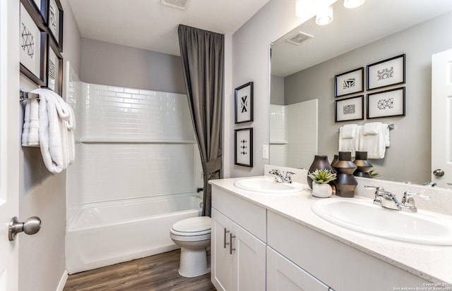 bathroom featuring toilet, wood finished floors, a sink, and shower / tub combo with curtain