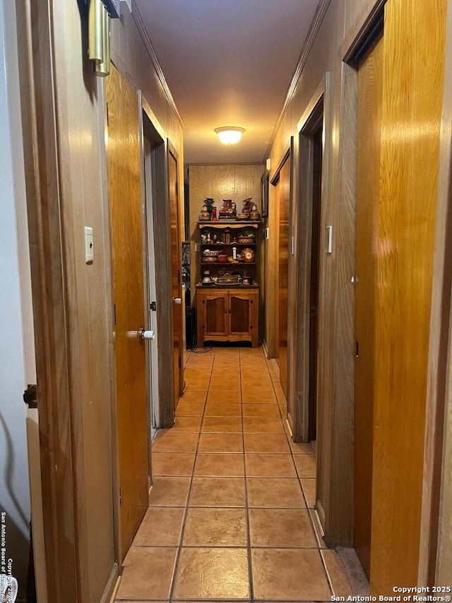 corridor featuring ornamental molding and light tile patterned flooring