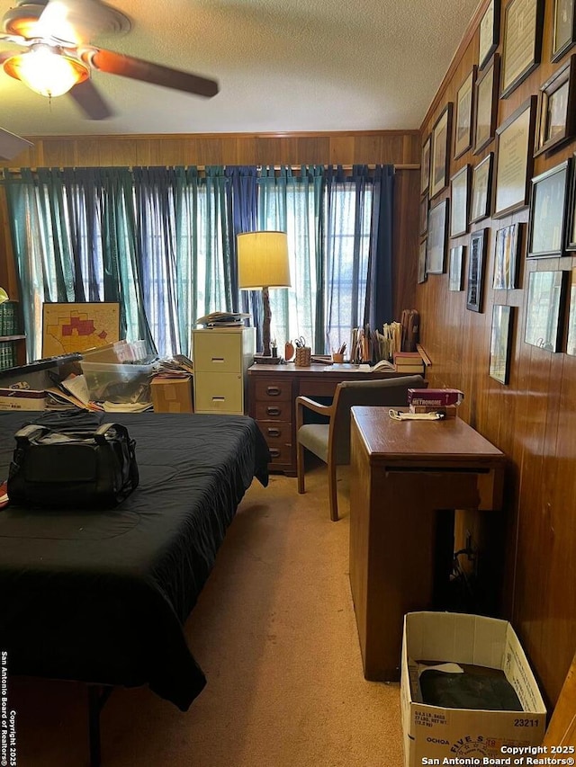 bedroom with wooden walls, a textured ceiling, and light colored carpet