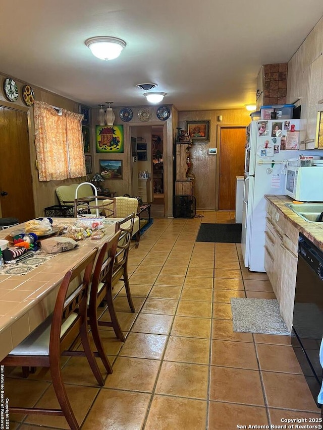 kitchen featuring tile countertops, light tile patterned floors, white appliances, and visible vents