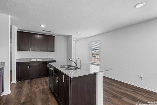 kitchen with a kitchen island with sink, a sink, visible vents, and dark brown cabinetry