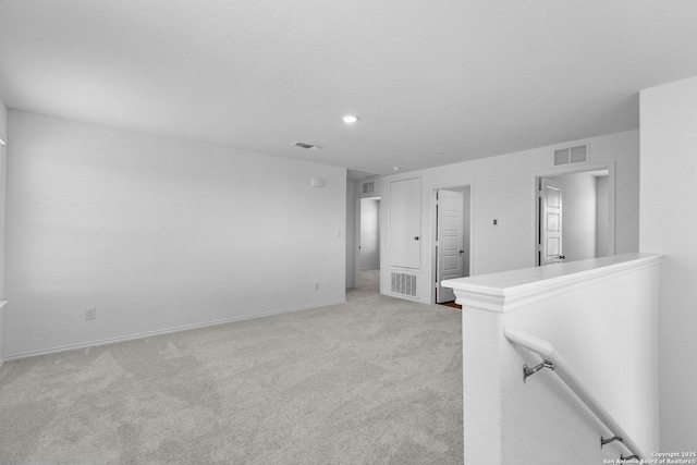 unfurnished room with visible vents, light carpet, and baseboards