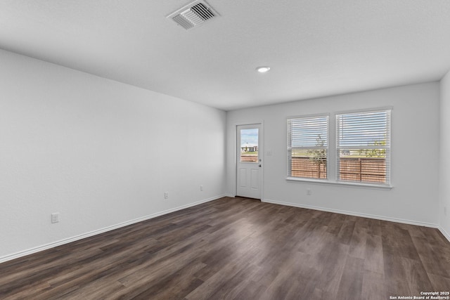 unfurnished room featuring dark wood-style floors, baseboards, and visible vents