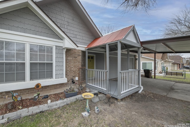 view of property exterior with driveway, metal roof, a porch, a carport, and brick siding