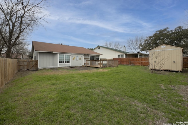 rear view of property with a storage shed, a lawn, a fenced backyard, a wooden deck, and an outdoor structure