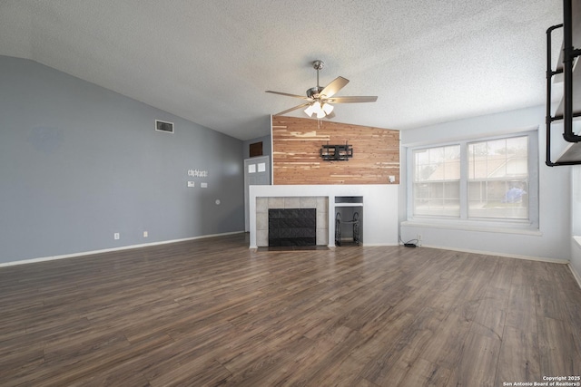 unfurnished living room featuring lofted ceiling, dark wood finished floors, a tile fireplace, and visible vents