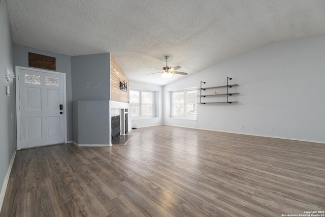 unfurnished living room featuring a fireplace, lofted ceiling, dark wood-type flooring, ceiling fan, and a textured ceiling