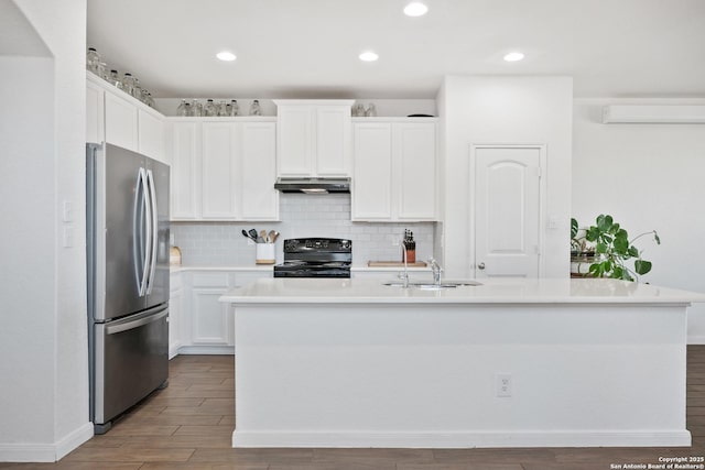 kitchen featuring black range, under cabinet range hood, white cabinetry, freestanding refrigerator, and light countertops