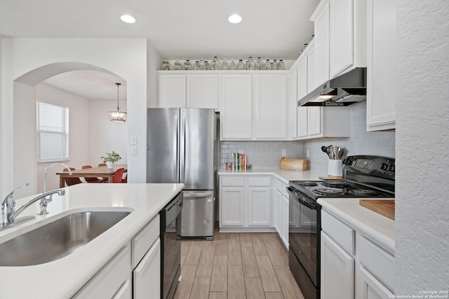 kitchen featuring under cabinet range hood, white cabinets, black appliances, and a sink