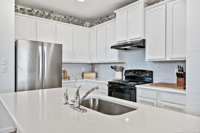 kitchen featuring under cabinet range hood, black range with electric stovetop, tasteful backsplash, and freestanding refrigerator