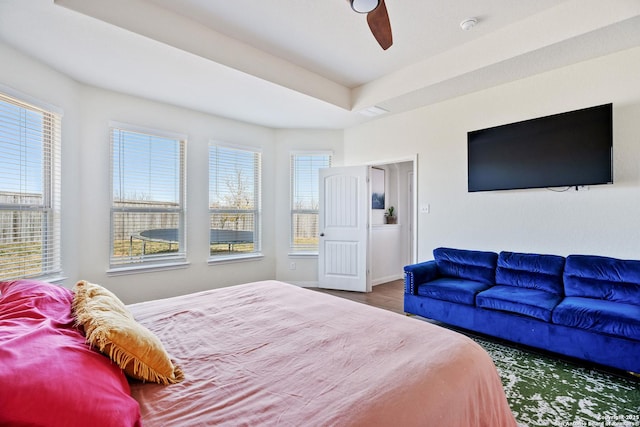 bedroom featuring ceiling fan, a raised ceiling, baseboards, and wood finished floors