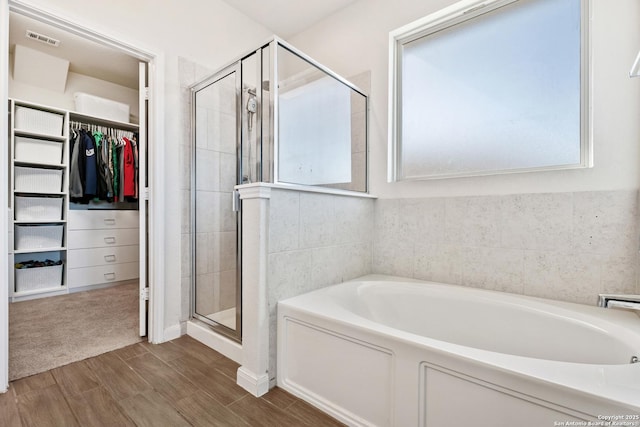 bathroom with visible vents, a stall shower, a spacious closet, and a bath