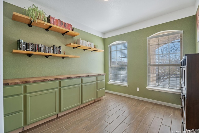 kitchen featuring green cabinetry, baseboards, wooden counters, and wood tiled floor