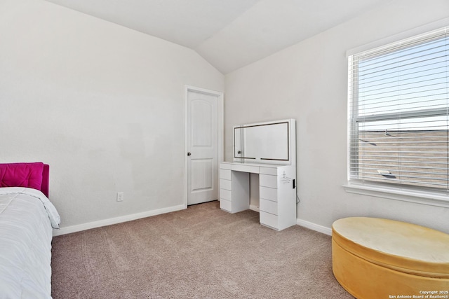 bedroom featuring light colored carpet, baseboards, and vaulted ceiling