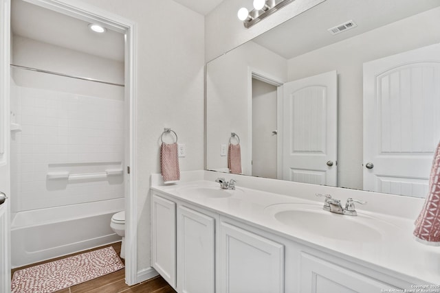 bathroom featuring double vanity, wood finished floors, visible vents, and a sink