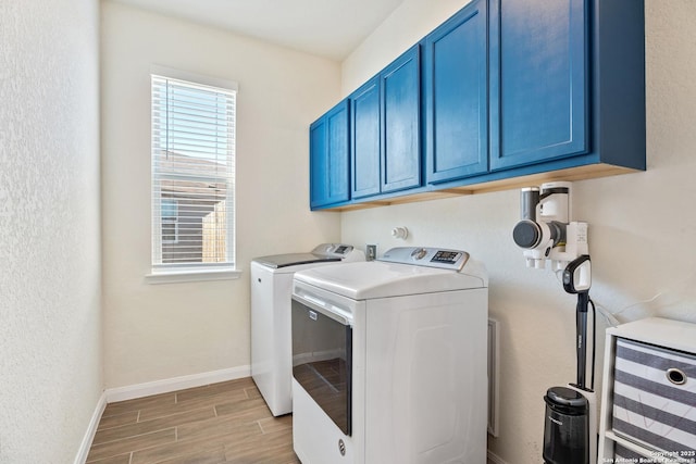 laundry room featuring cabinet space, baseboards, wood finish floors, and separate washer and dryer