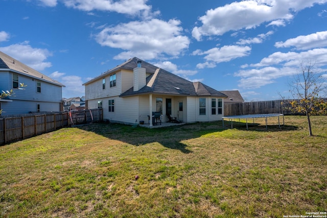 back of property featuring a yard, a fenced backyard, a patio area, and a trampoline