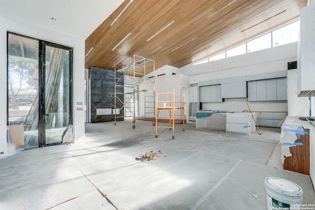 interior space featuring concrete flooring, a high ceiling, and wooden ceiling