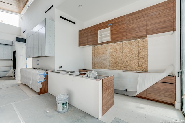 kitchen with concrete floors, modern cabinets, a towering ceiling, and brown cabinets