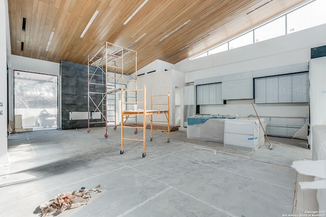 misc room featuring concrete floors, wooden ceiling, and a towering ceiling