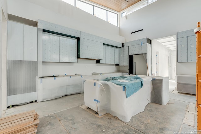 kitchen with gray cabinetry, a towering ceiling, and unfinished concrete floors