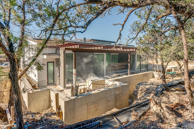 rear view of property featuring a sunroom and stucco siding