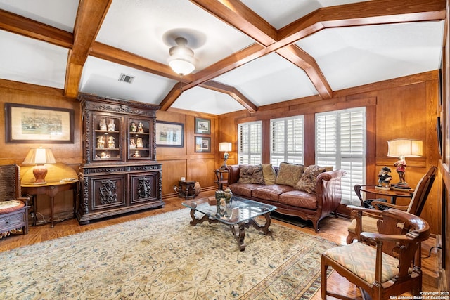 living area with wooden walls, visible vents, coffered ceiling, and beam ceiling