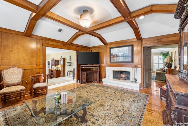 living room featuring wood walls, coffered ceiling, and visible vents