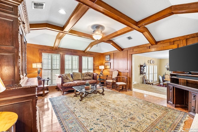 living area featuring coffered ceiling, beam ceiling, visible vents, and wooden walls