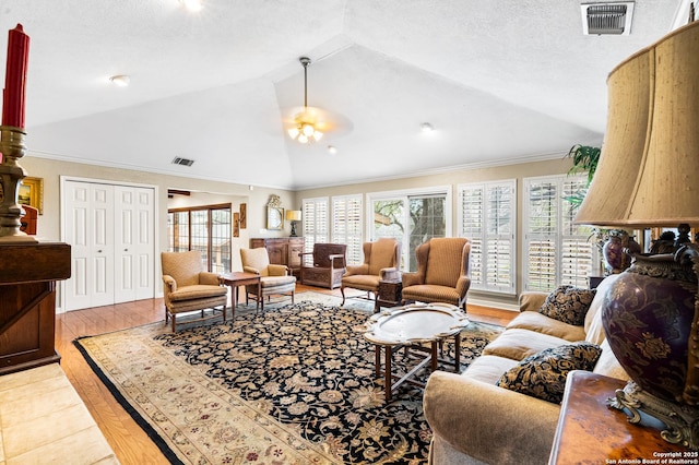 living area featuring light wood-style floors, visible vents, high vaulted ceiling, and a textured ceiling