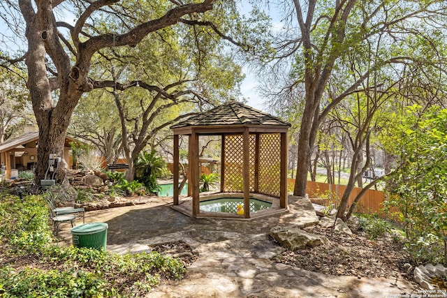 view of yard with a gazebo, fence, and an in ground hot tub