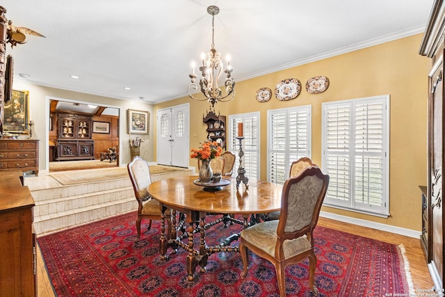 dining room with baseboards, ornamental molding, a notable chandelier, and wood finished floors