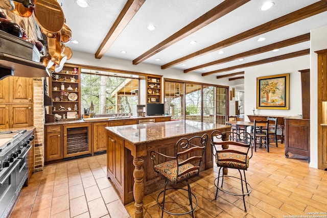 kitchen with wine cooler, a breakfast bar area, a center island, light stone countertops, and open shelves