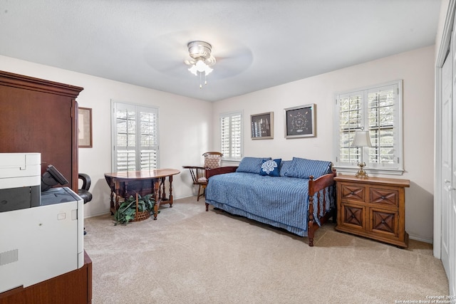 bedroom with light carpet, a ceiling fan, and baseboards