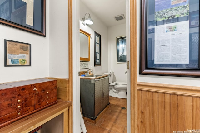 hallway featuring tile patterned flooring, visible vents, and a sink