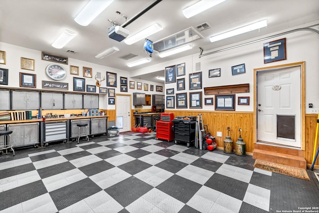 garage with wood walls, visible vents, a workshop area, and wainscoting