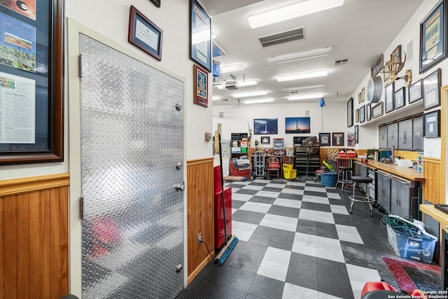 misc room featuring dark floors, a wainscoted wall, visible vents, built in study area, and a workshop area