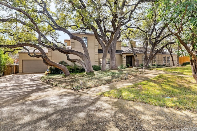 view of front facade featuring a garage, fence, driveway, stucco siding, and a chimney