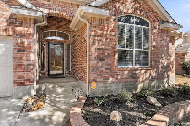 view of exterior entry featuring brick siding and an attached garage