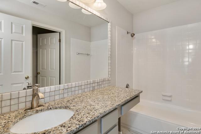bathroom featuring backsplash, visible vents, vanity, and walk in shower