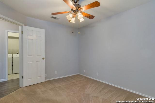 spare room with visible vents, baseboards, ceiling fan, carpet, and separate washer and dryer